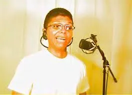 A young man in front of a microphone, singing with headphones on
