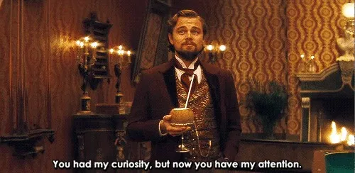 Leonardo DiCaprio as Calvin Candie, leaning forward with interest, with a subtitle