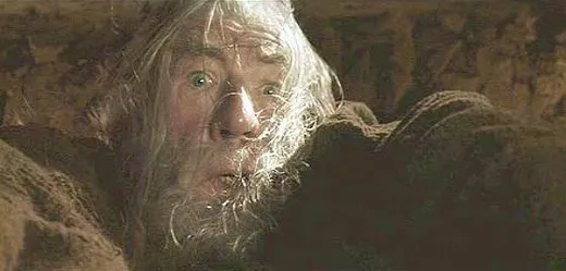 Gandalf hanging from the edge of a broken stone bridge, looking up