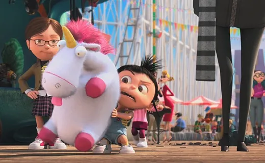 A little girl hugging a huge fluffy toy unicorn at a fairground