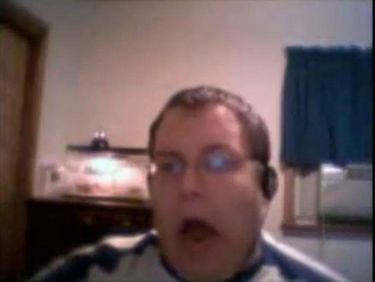 A young man in headphones lip-syncing enthusiastically in front of a webcam