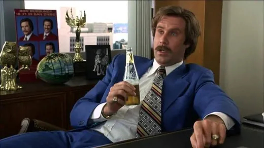 Ron Burgundy in a suit, standing in an office looking dazed