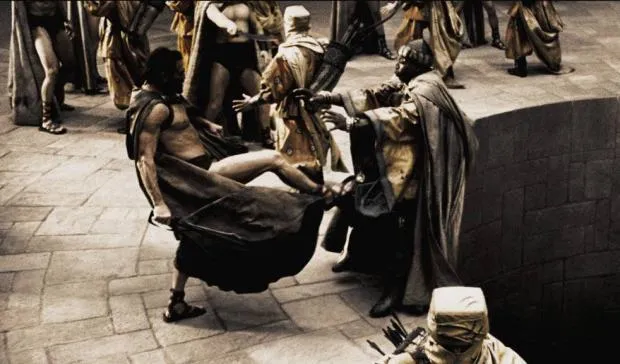 King Leonidas kicking a Persian messenger backwards into a deep pit, with soldiers watching